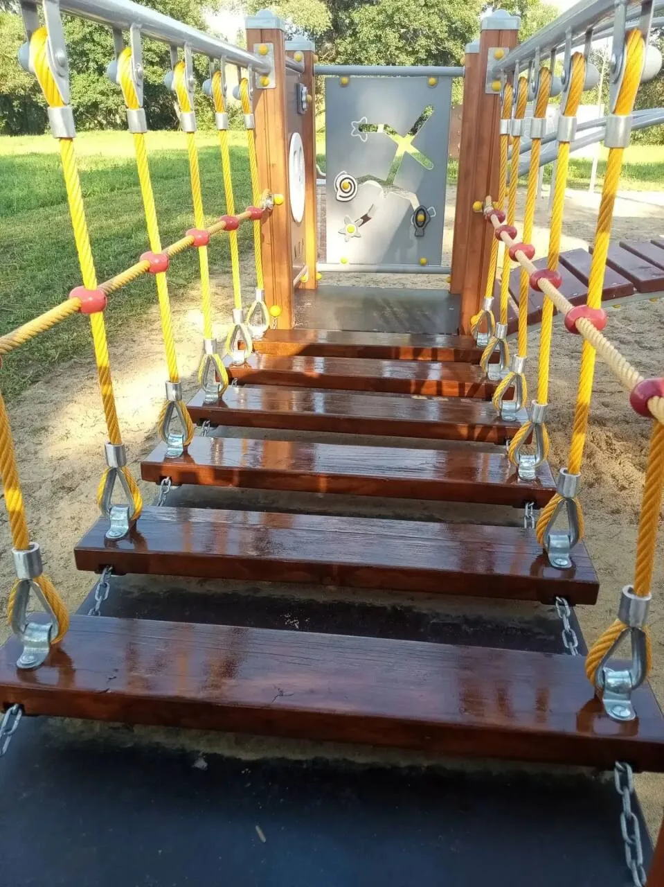 Покрытые лаком деревянные ступени подвесного моста на детской площадке в Шелково Ривер